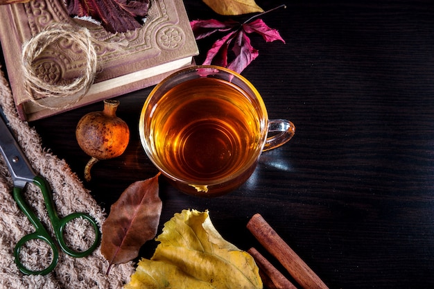 Une tasse de thé avec des feuilles d'automne et un livre