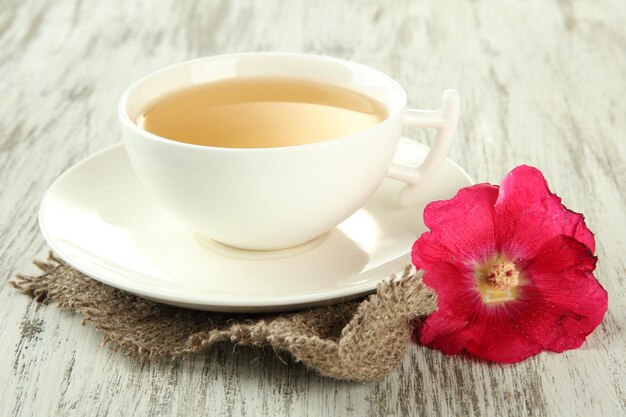 Tasse de thé et fleur de mauve rose sur fond de bois