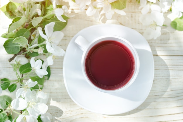 Tasse de thé et fleur de pommier sur un fond en bois. Vue de dessus