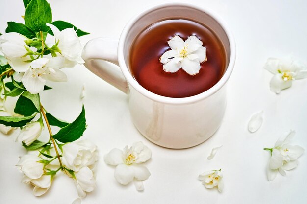 Tasse à thé avec des fleurs de jasmin sur fond blanc. Vue de dessus