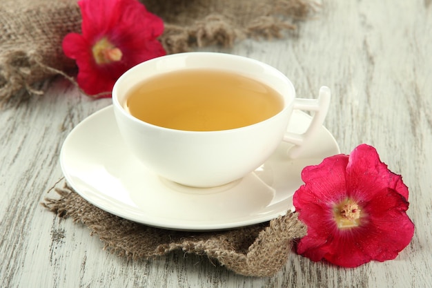 Tasse de thé et fleurs de mauve rose sur fond de bois