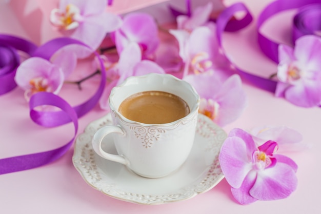 tasse de thé et de fleurs d'orchidées volantes sur rose clair