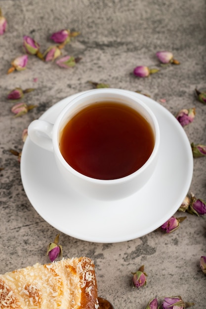 Une tasse de thé avec des fleurs séchées placées sur une table en pierre.