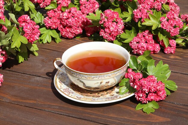 tasse de thé sur fond de bois marron avec des fleurs roses