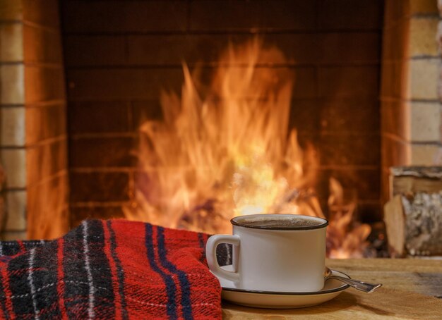 Une tasse de thé et de laine près d'une cheminée confortable dans une maison de campagne vacances d'hiver ou d'automne