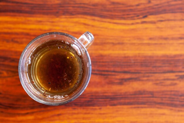 Tasse de thé avec des lames de thé flottantes sur la table à plat photo horizontale