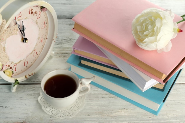 Tasse de thé avec des livres et horloge sur fond de bois