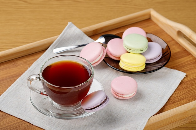 Tasse de thé et macarons colorés sur un plateau en bois Thé du matin et bonbons