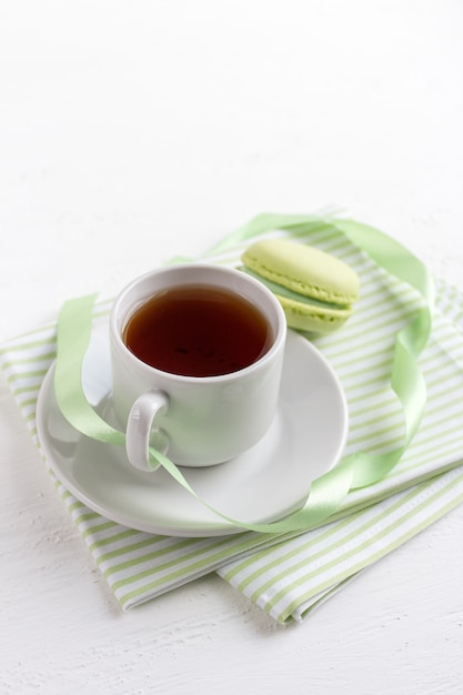 Tasse de thé et macarons français verts sur un bois blanc