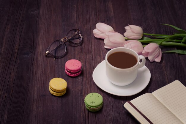 Tasse de thé, macarons, verres, tulipes roses