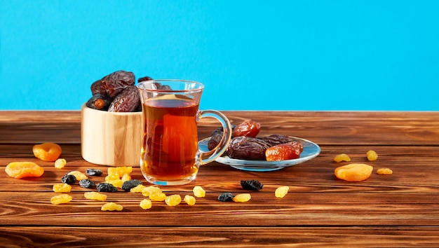 Une tasse de thé et un mélange de fruits secs dans une assiette sur une table en bois