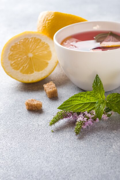 Tasse de thé, menthe et citron sur une table grise avec espace de copie