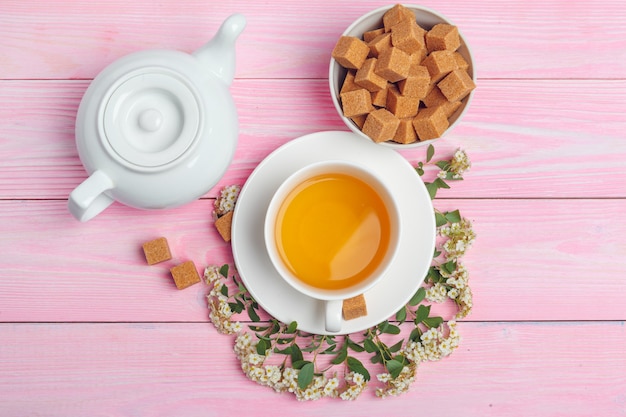 Tasse de thé avec des morceaux de sucre et des branches de fleurs sur la table en bois se bouchent