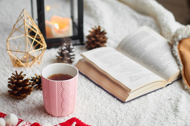 Tasse de thé de nature morte à la maison confortable et livre ouvert avec plaid chaud. Vacances d'hiver