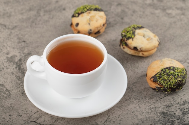Une tasse de thé noir et des biscuits placés sur une table en pierre.