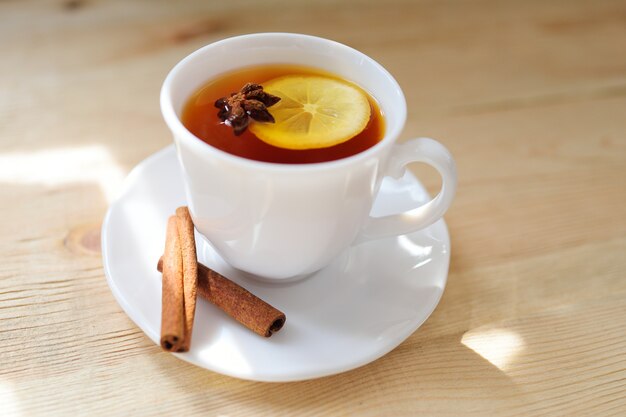 Une tasse de thé noir avec un citron à la cannelle et un badan sur une table en gros plan