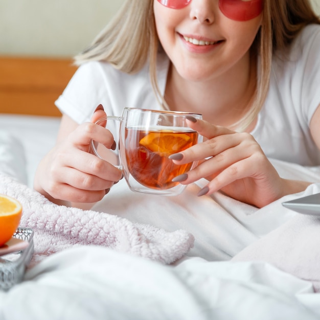 Tasse de thé noir dans les mains des femmes. Une jeune femme prend son petit-déjeuner, boit un lit de thé à la maison.