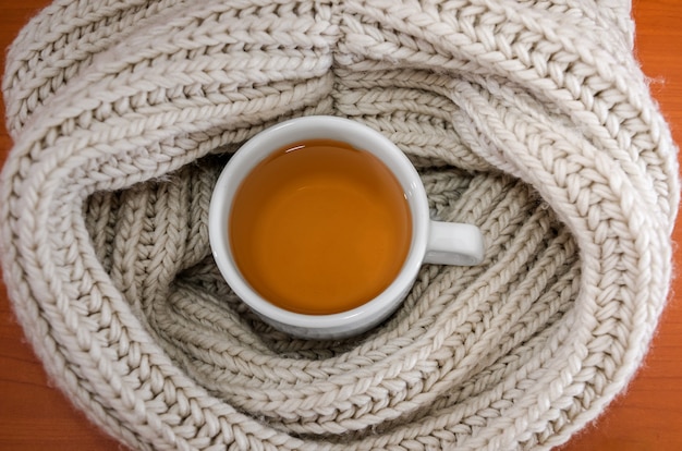 Tasse de thé noir enveloppée dans une écharpe tissée chaude, vue de dessus