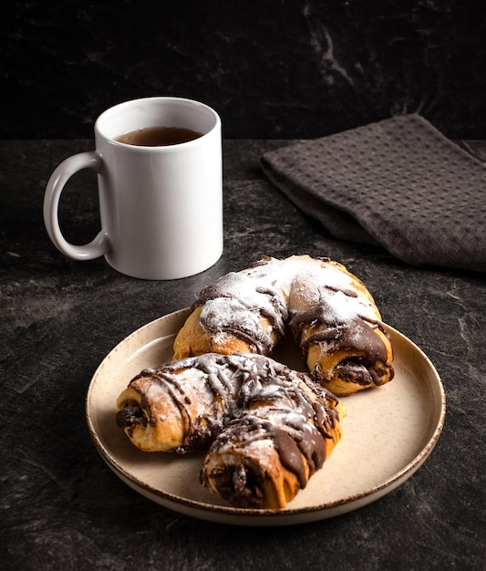 Photo tasse de thé noir pâtisseries au chocolat traditionnelles sur fond sombre