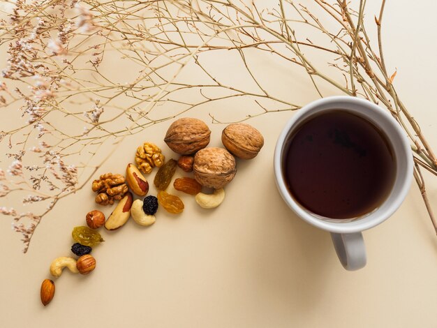 Tasse de thé, noix et raisins secs à côté de fleurs séchées