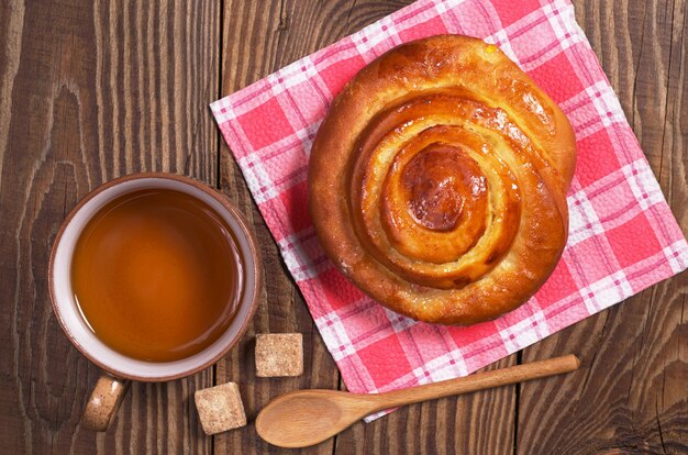 Tasse de thé et pain frais pour le petit déjeuner sur table en bois, vue de dessus