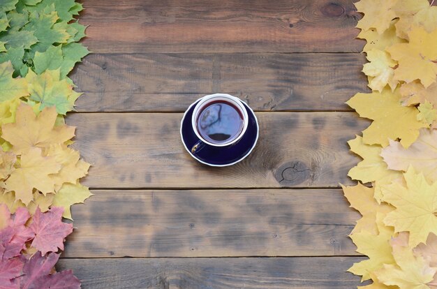 Une Tasse De Thé Parmi Un Ensemble De Feuilles Tombées D'automne Tombées Sur Un Fond Jaunissant