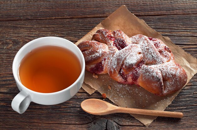 Tasse de thé et petit pain avec de la confiture sur une table en bois rustique