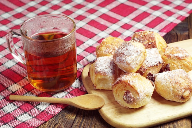 Tasse à thé et petits gâteaux aux raisins secs sur nappe rouge