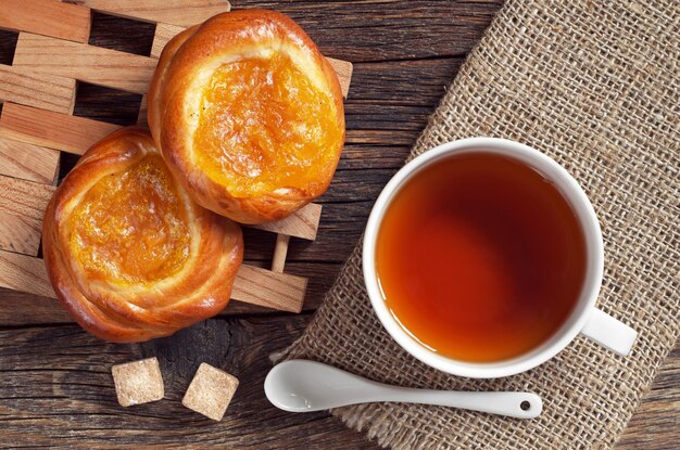 Tasse de thé et petits pains avec de la confiture sur la vieille vue de dessus de table en bois