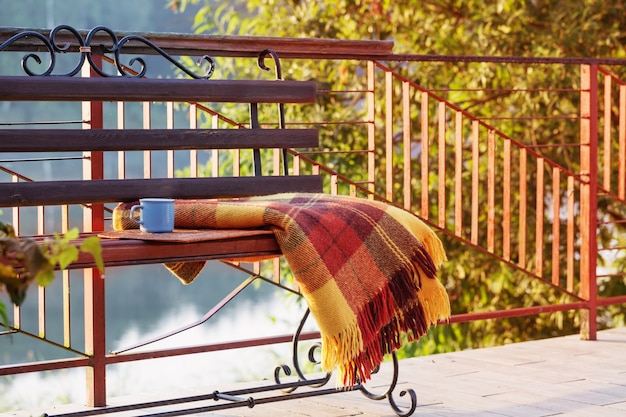 Tasse de thé et plaid chaud sur le banc en bois extérieur