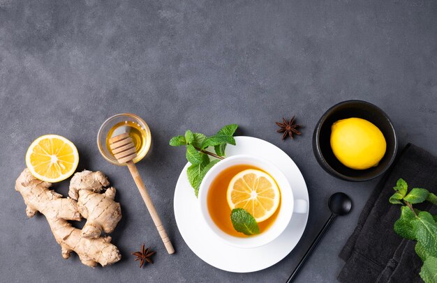 Tasse de thé à plat avec miel de citron et menthe sur fond sombre Le concept d'une boisson saine pour l'immunité au gingembre et aux herbes