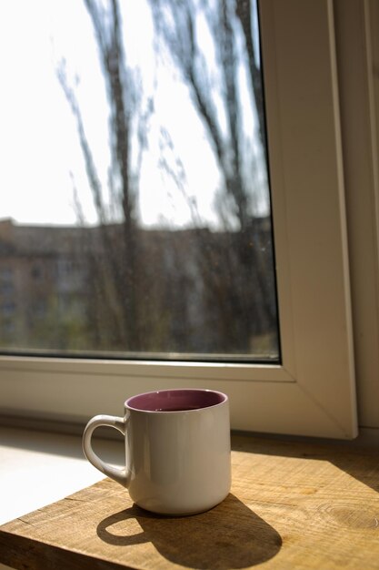 Une tasse de thé sur un plateau en bois se tient près de la fenêtre