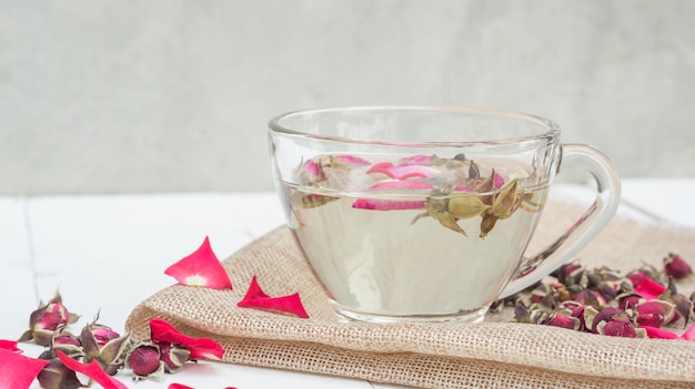 Une tasse de thé rose rose sur une table en bois blanche.