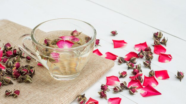 Une tasse de thé rose rose sur une table en bois blanche.