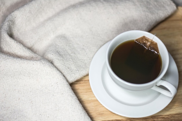 Tasse de thé avec sachet de thé trempé dans de l'eau chaude sur fond de tissu en bois et coton