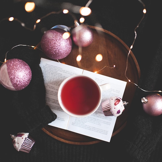 Tasse de thé savoureux sur un livre ouvert avec des décorations de Noël sur fond de pull noir se bouchent. Saison des vacances d'hiver. Joyeux Noël.