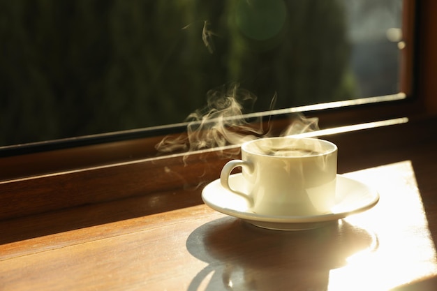 Une tasse de thé se dresse sur un rebord de fenêtre en bois