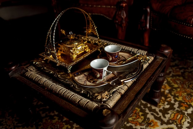 Tasse à thé et sucrier sur plateau sur une vieille petite table. Service à thé de style vintage. Un ancien service à thé en céramique et boîte en or. Concept de cérémonie du thé. Grand espace pour inscription ou logo