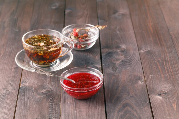 Tasse de thé sur table en bois avec confiture de framboise