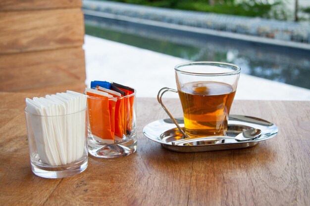 Tasse de thé sur table en bois avec du sucre et du papier de soie.