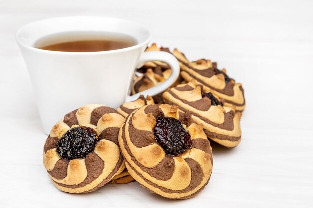 Tasse de thé et tas de biscuits avec de la confiture sur une table en bois blanc