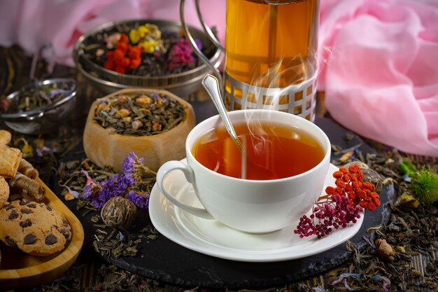 Une tasse de thé avec une tasse de thé sur une table à côté d'une bouteille de thé.