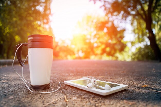 Tasse de thé, téléphone et casques se trouve sur la route