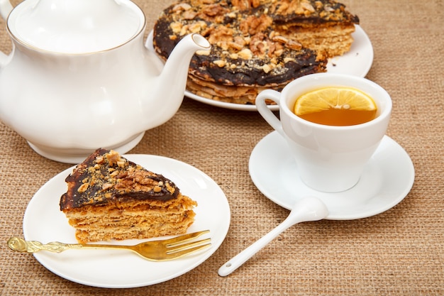 Tasse de thé, théière en porcelaine et gâteau feuilleté au chocolat maison sur table avec un sac