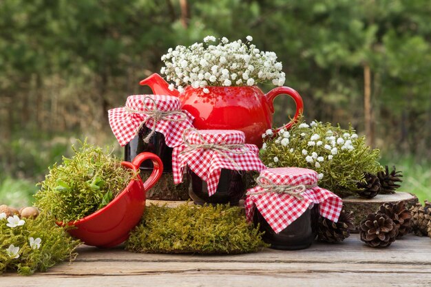 Tasse à thé théière rouge et trois pots de confiture saine Forêt sur fond