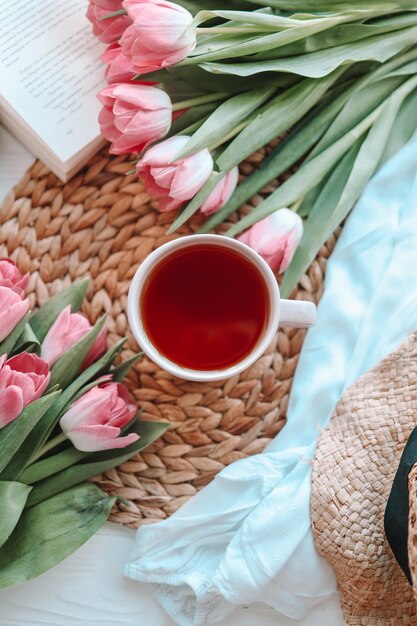 Une tasse de thé avec des tulipes sur fond rose