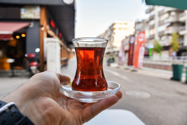 Photo tasse de thé turc à la main rues du matin thé noir d'antalya