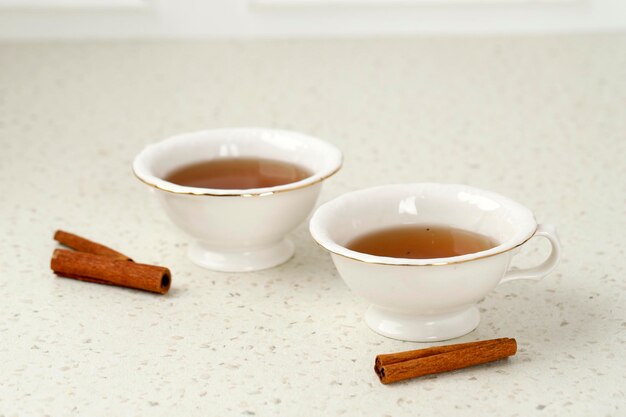 Tasse de thé en verre avec des bâtons de cannelle Fond blanc Isolé Gros plan Thé à la cannelle épicé chaud