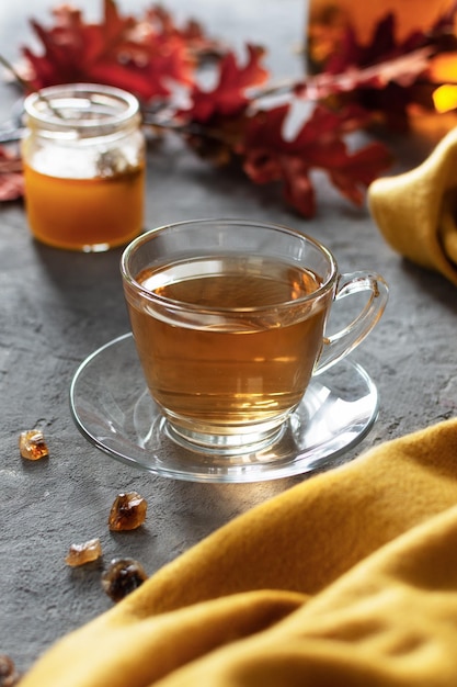 Une tasse de thé en verre avec du miel sur une table grise