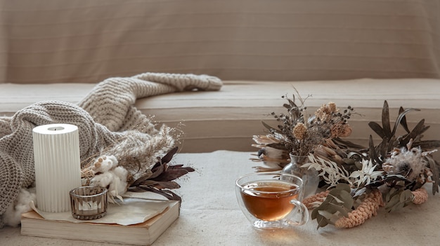 Tasse de thé en verre, élément tricoté et fleurs séchées à l'intérieur de la pièce